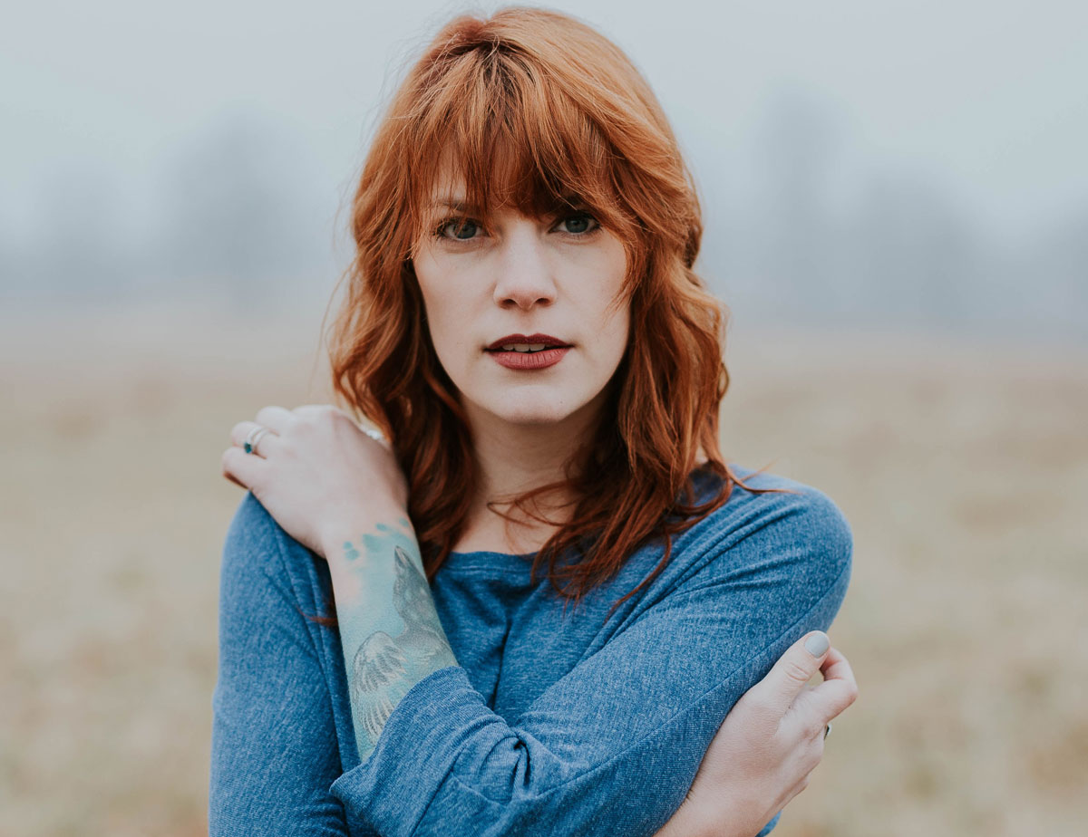 image of woman with red hair looking into camera for a blog article defining the difference between 12 step traditional recovery modalities vs a non-12 step holistic recovery program.