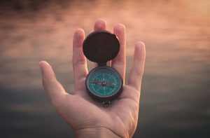 image of man holding a compass for a blog article entitled "Holistic Drug Rehab vs 12-Step Drug Rehab" for Gulf Breeze Recovery