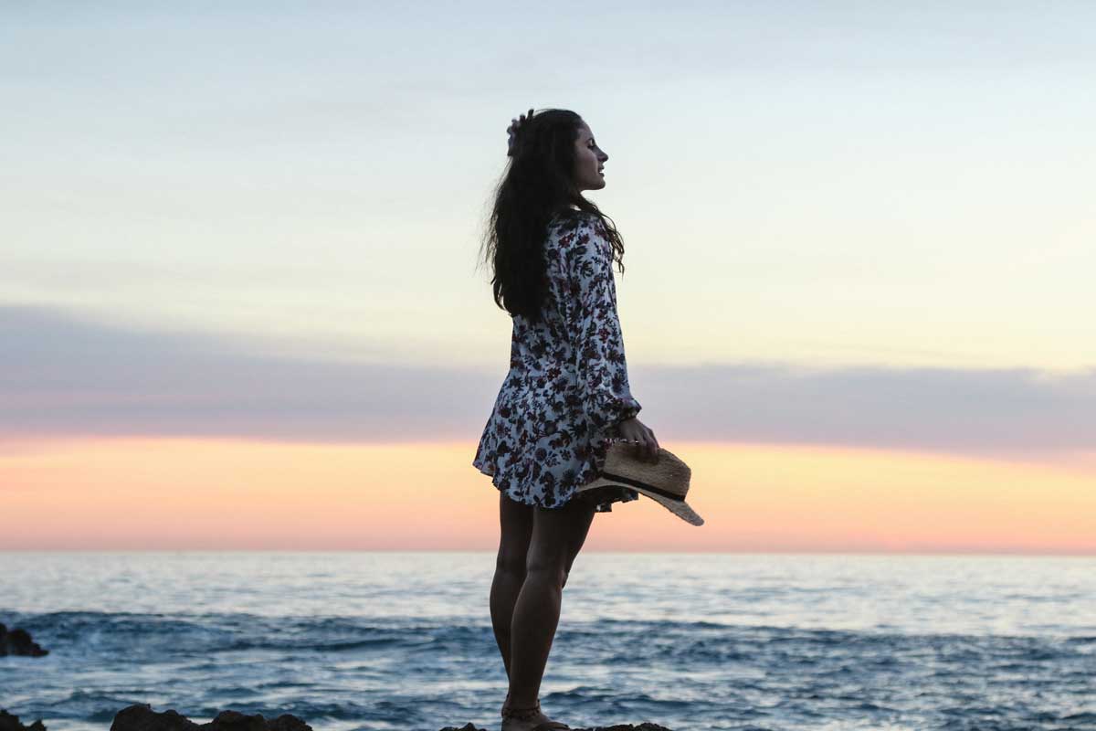 woman standing on the beach enjoying the sunset for a blog article entitled "Why a Holistic Drug and Alcohol Rehabilitation Program?" for Gulf Breeze Recovery.