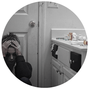 dramatic image of shabby bathroom with woman holding her head in her hands surrounded by prescription meds and pill bottles for a blog article entitled: "How Many People Take Drugs to Alter Mood" for Gulf Breeze Recovery's holistic, non 12 step drug rehab