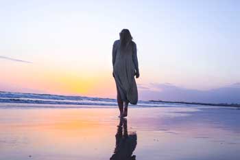 a woman enjoying a relaxing and calming walk on beach for a blog article entitled: Addiction and Aha Moments" for Gulf Breeze Recovery, a non 12 step holistic drug rehab