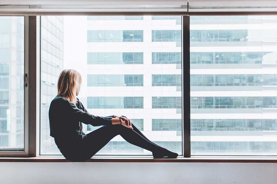 image of woman gazing out an office window for blog article for Gulf Breeze Recovery a non 12 step alternative drug rehab entitled "Why We Always Want To Be Somewhere Else"