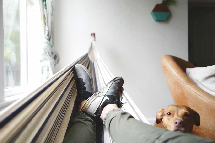 image of man relaxing on hammock inside of apartment for blog article for Gulf Breeze Recovery a non 12 step alternative drug rehab entitled "Why We Always Want To Be Somewhere Else"