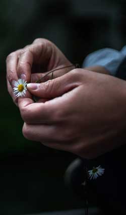 photo of woman holding a small wild flower for a blog article for Gulf Breeze Recovery's non 12 step holistic drug treatment program called THRIVE® Total Health Recovery entitled "Why Overthinking Things Is Wasting Your Time and 5 Ways to Stop."
