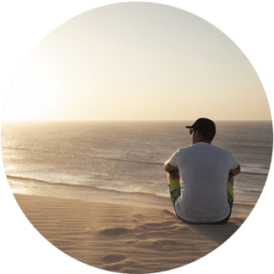 young man sitting a beautiful beach at sundown extremely serene for Gulf Breeze Recovery non 12 step holistic drug and alcohol rehab program called THRIVE® Total Health Recovery