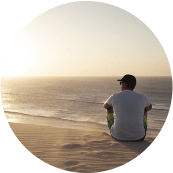 image of young man sitting a beautiful beach at sundown extremely serene for Gulf Breeze Recovery non 12 step holistic drug and alcohol rehab program called THRIVE® Total Health Recovery