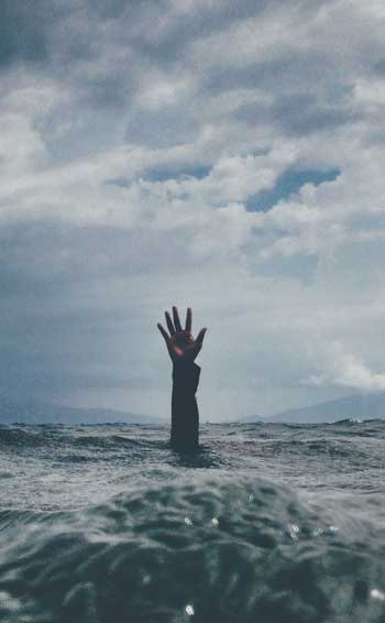 image of man's arm reaching out of a stormy sea for a blog article entitled "The four components of holistic recovery" for Gulf Breeze Recovery a non 12 step holistic drug rehab