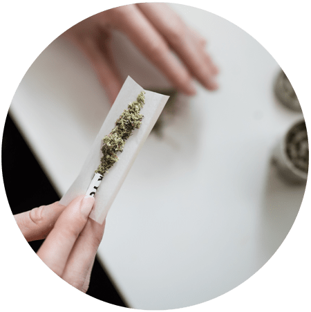 The Rush to Legalize Marijuana image female hands rolling joint exhaling cloud of smoke for Gulf Breeze Recovery non-12 step holistic drug and alcohol rehab program THRIVE® Total Health Recovery