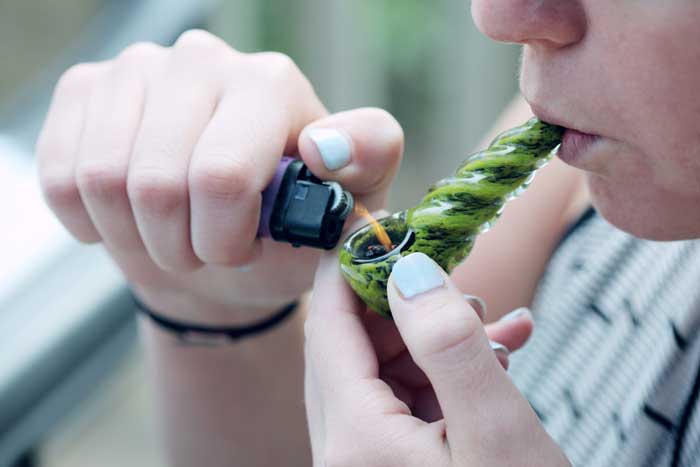 The Rush to Legalize Marijuana image of young woman smoking joint exhaling cloud of smoke for Gulf Breeze Recovery non-12 step holistic drug and alcohol rehab program THRIVE® Total Health Recovery