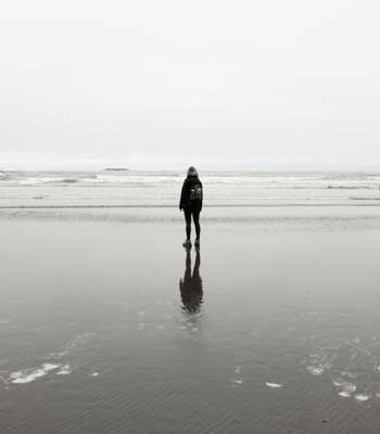 an image of person enjoying serenity alone on a uncluttered beach for blog article entitled "What do we lose by numbing a feeling?" for Gulf Breeze Recovery non-12 step holistic drug and alcohol rehab