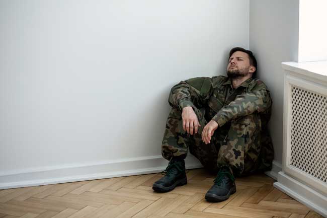 image of depressed soldier sitting in corner of empty room for Gulf Breeze Recovery non-12 step holistic drug and alcohol treatment center