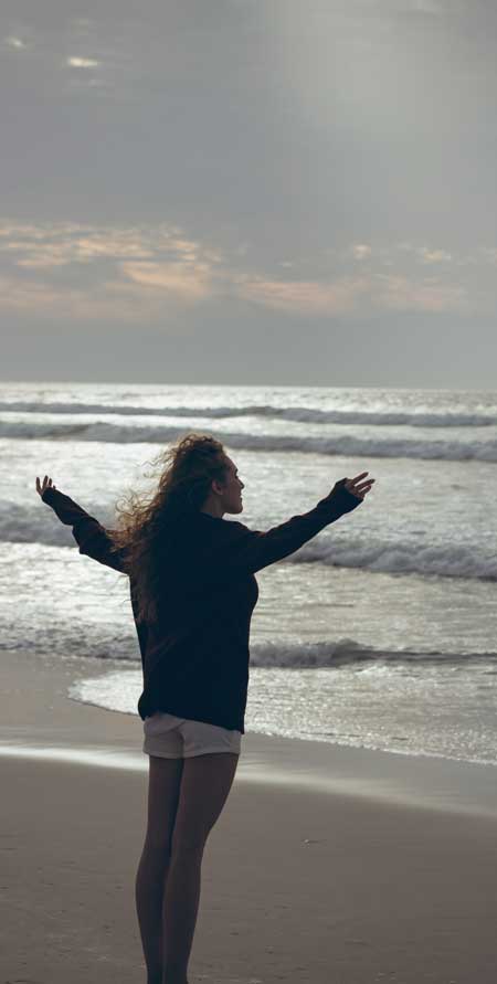 image of a woman on the beach at sunset with arms outstretched for Gulf Breeze Recovery non-12 step holistic drug and alcohol treatment center in Florida