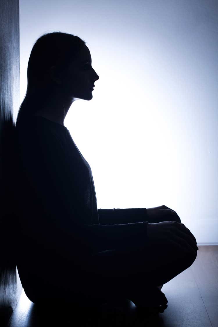 image of woman in silo with back to wall considering addiction treatment