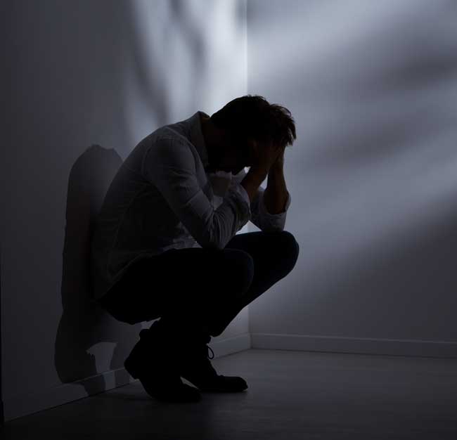 sad man sitting alone against a wall