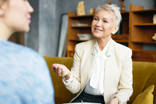 happy and smiling woman explaining the non 12-step approach to rehab to younger woman