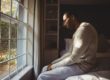 man kneeling by his window suffering from post-acute withdrawal syndrome