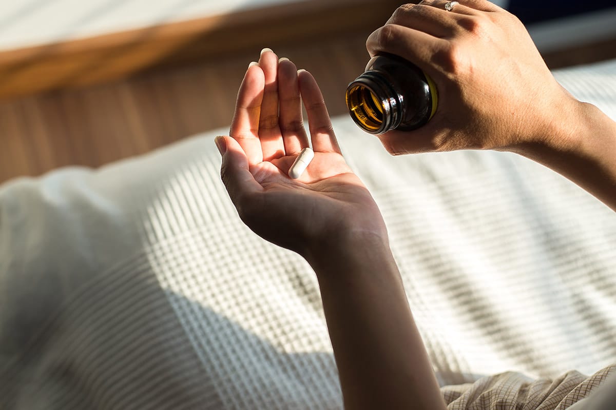 a person putting pills into their hand suffering from prescription drug abuse