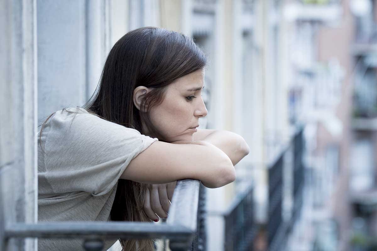 a woman looking out of her balcony displaying the signs of ptsd in women