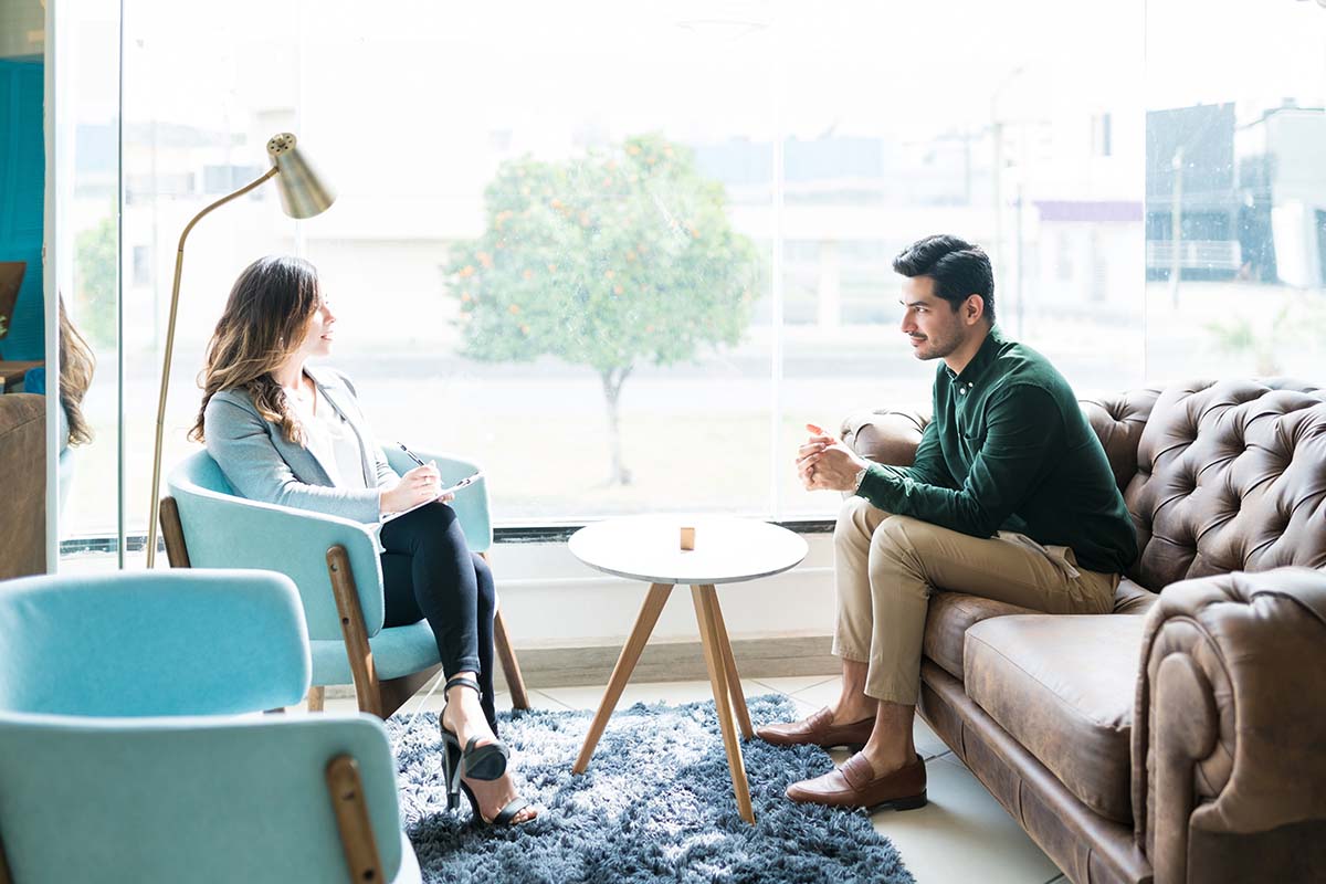 female therapist in sunny office explaining the 5 benefits of outpatient rehab to a younger man