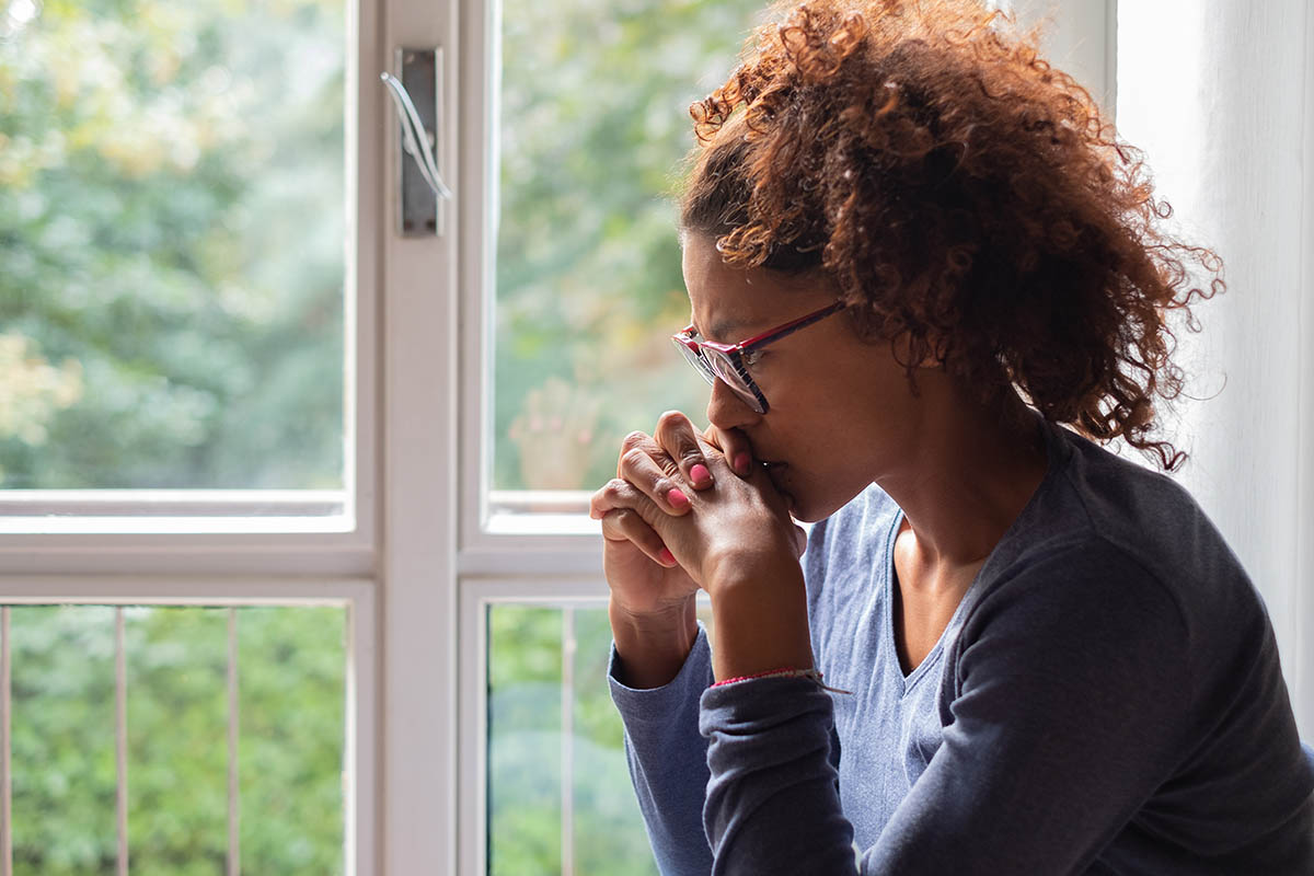 Woman sitting beside sunny window contemplating the common dangers of fentanyl