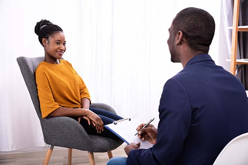 therapist in well-lit office discussing a depression treatment center with a client.