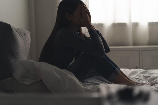 woman sitting alone in dark room living with depression