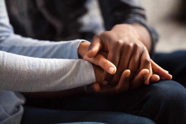 close up of one person's hands clasping another person's hands as a gesture of the importance of forgiveness in recovery