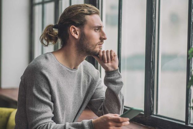 Man looks out a window while pondering the question, "What is drug detox?"
