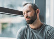 Man near window pondering the signs of opioid addiction