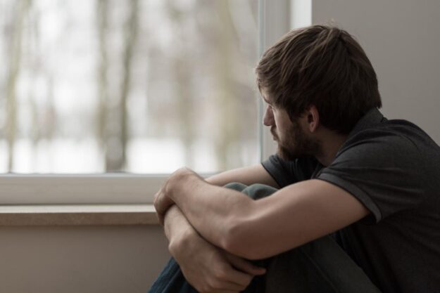 Man looking out from window, needing heroin addiction help