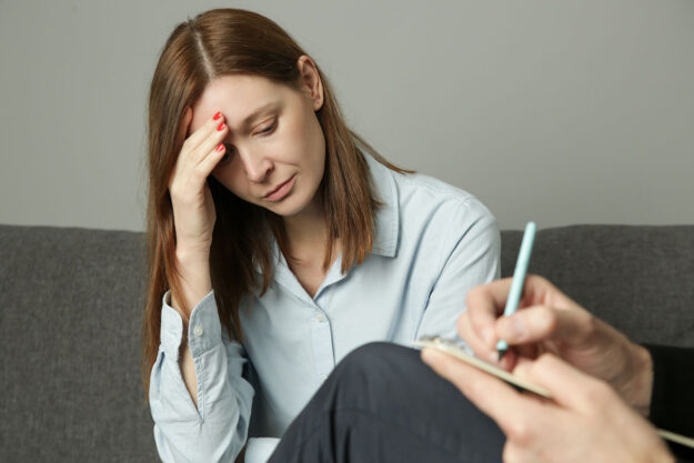 Woman sits on couch in shame as she talks to therapist about obstacles to substance abuse treatment