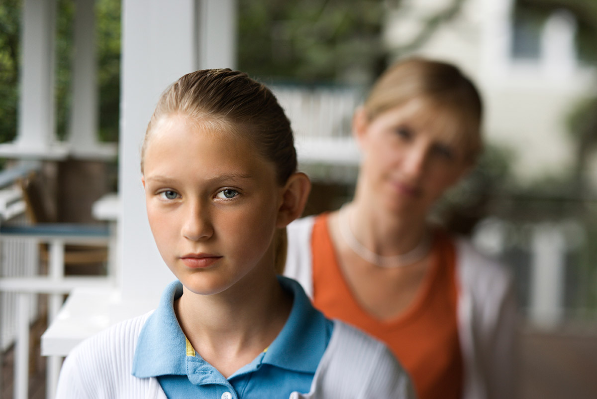 Girl stands in front her mother, one of the many children of alcoholics