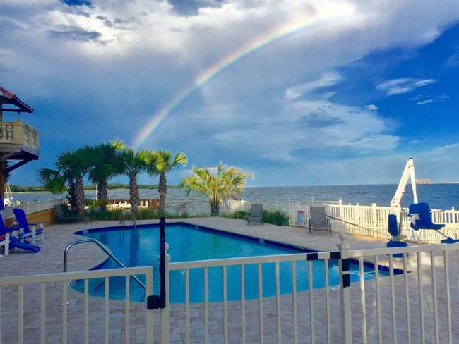 image of rainbow over waterside exterior of Gulf Breeze Recovery's facility