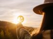 Person holding a smiley face up to the sunset to symbolically break the stigma of addiction