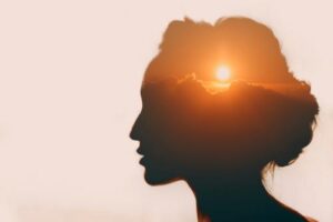 Silhouette of woman's head in profile with a beautiful sunset where the brain should be to illustrate the calming effects of trauma therapy 