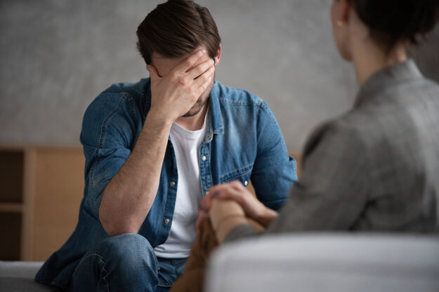 Client in therapy with hand on forehead discussing addiction to the most addictive drugs