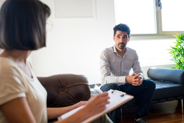 Person in therapy with counselor learning answers to the question how long is inpatient drug rehab