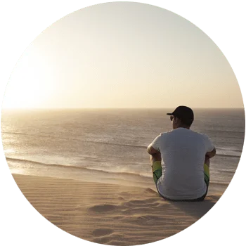 young man sitting a beautiful beach at sundown extremely serene for Gulf Breeze Recovery non 12 step holistic drug and alcohol rehab program called THRIVE® Total Health Recovery