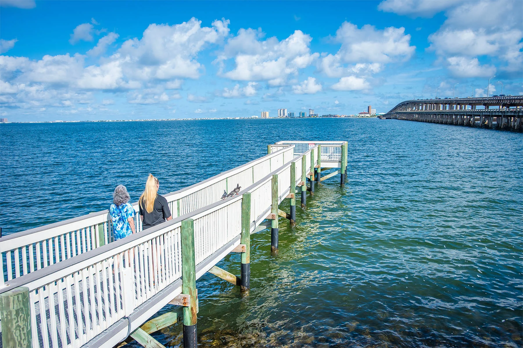 Two people walking along dock on the water