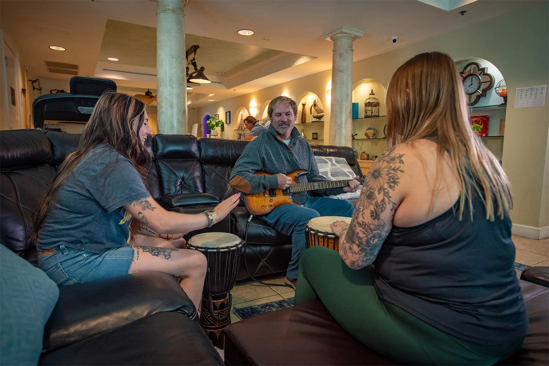 Three people sitting on a couch playing musical instruments