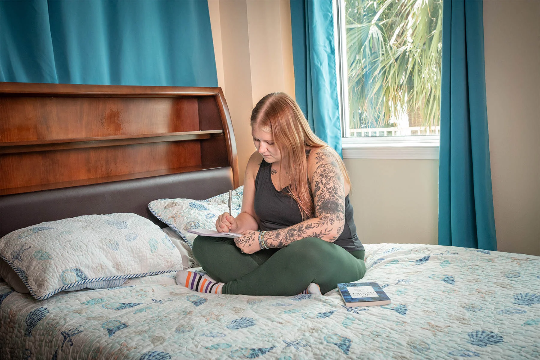 Woman writing in notebook on bed