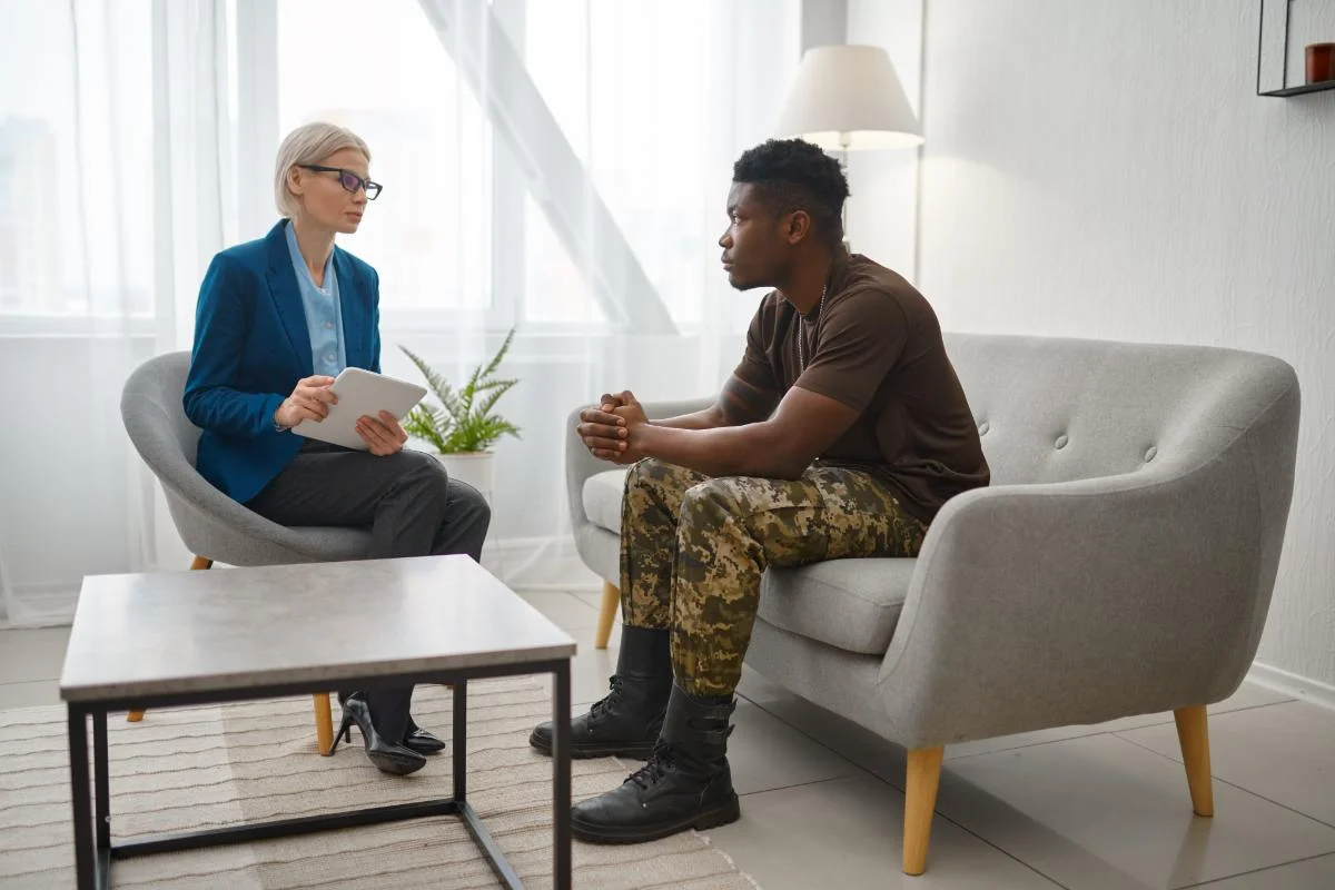 A veteran getting therapy while sitting on a couch. He's talking to a therapist.