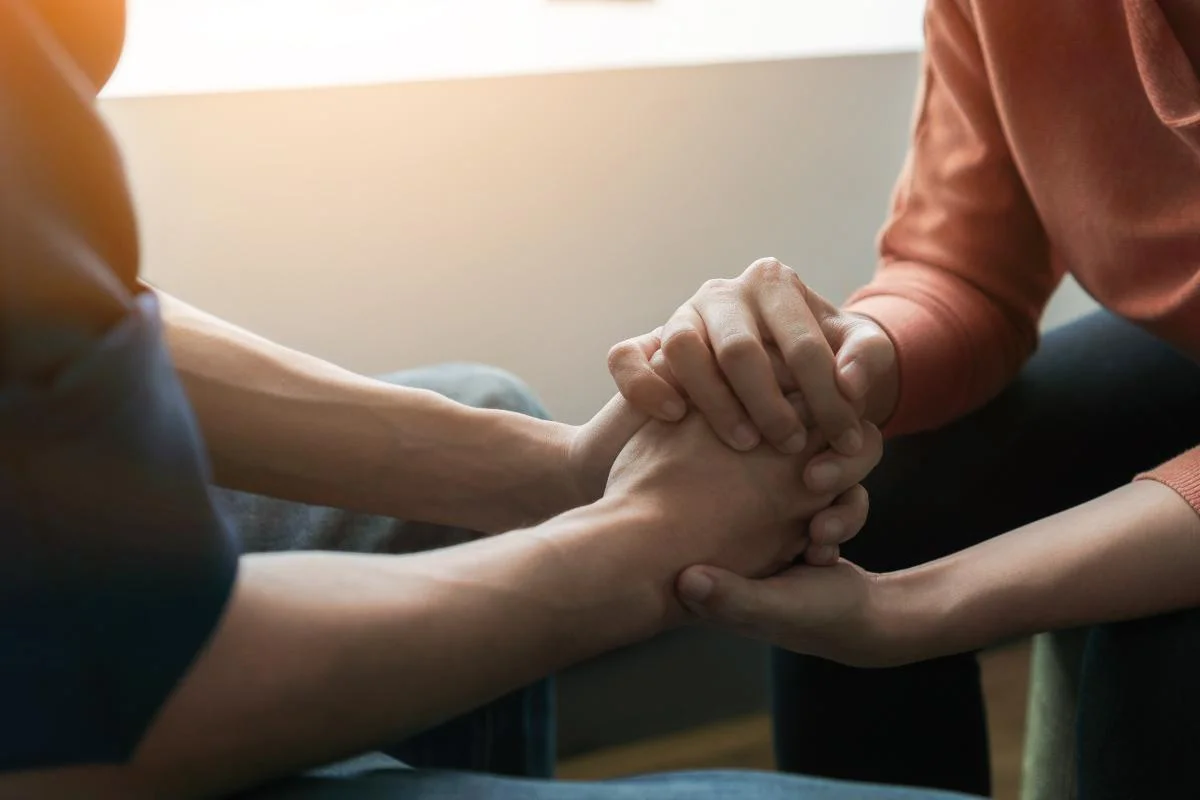Hands clasped as one person learns how to help someone with opioid addiction