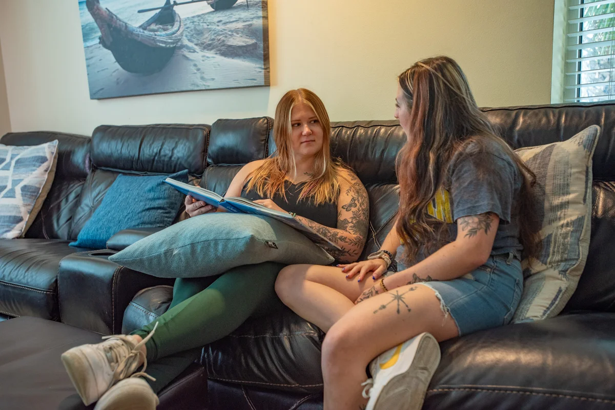 Two women sitting on couch reading book