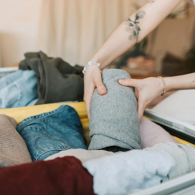 Tattoo'd person packing suitcase